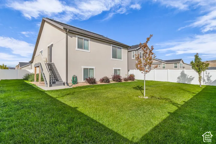 Expansive grassy yard with mature trees, a white perimeter fence, and access to an elevated outdoor deck with stairs
