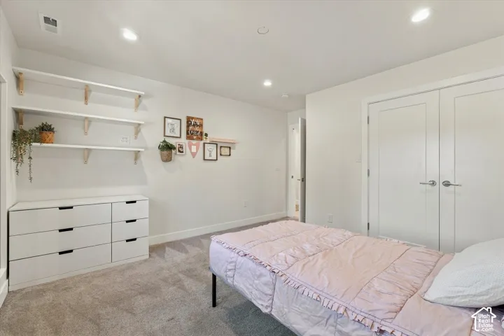 Recessed ceiling lighting, soft gray carpeting, white walls, and white double doors