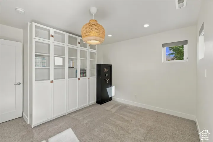 White built-in cabinetry with glass-front doors, recessed lighting, and a woven pendant light fixture