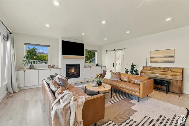 Recessed lighting, wood-finish flooring, and a fireplace with a tile surround and wood mantel