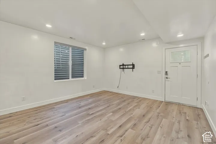 Wood-finish flooring, white walls, recessed lighting, and a white entry door with a clear glass insert
