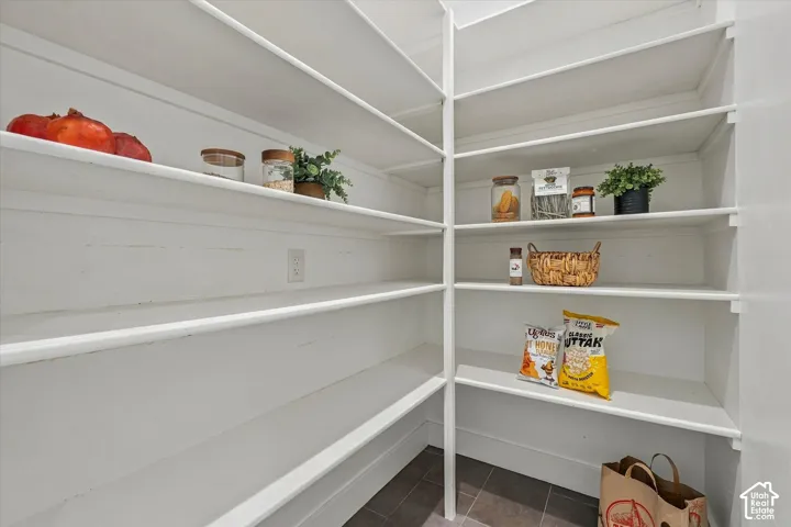 Expansive pantry with white shelving and dark tile flooring