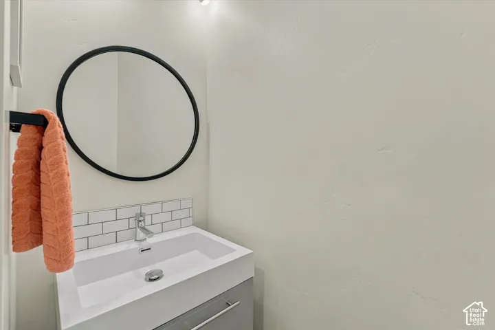 Wall-mounted vanity with integrated sink, subway tile backsplash, and circular mirror with black frame