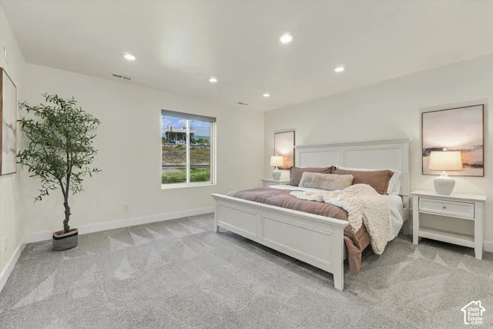 Recessed ceiling lighting, white painted walls, large window, and light gray carpeted flooring