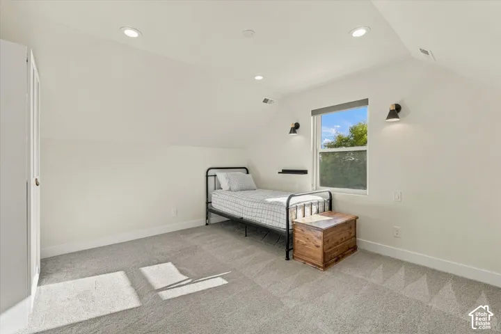 Recessed lighting, wall-mounted sconces, carpet flooring, a window with a roller shade, and built-in cabinetry