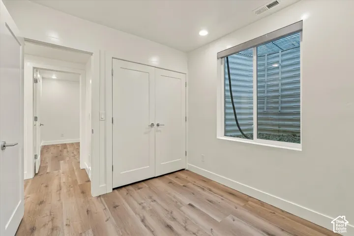 Room with wood-finish flooring, recessed lighting, and a window well with gravel