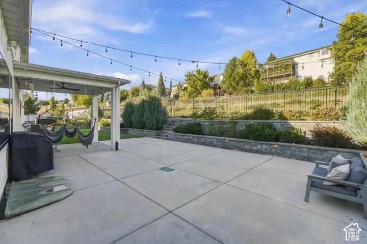 Expansive concrete patio featuring a covered outdoor area with a ceiling fan