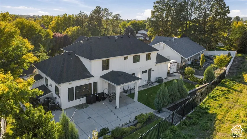 Expansive patio with geometric paving, covered outdoor area, and established plantings