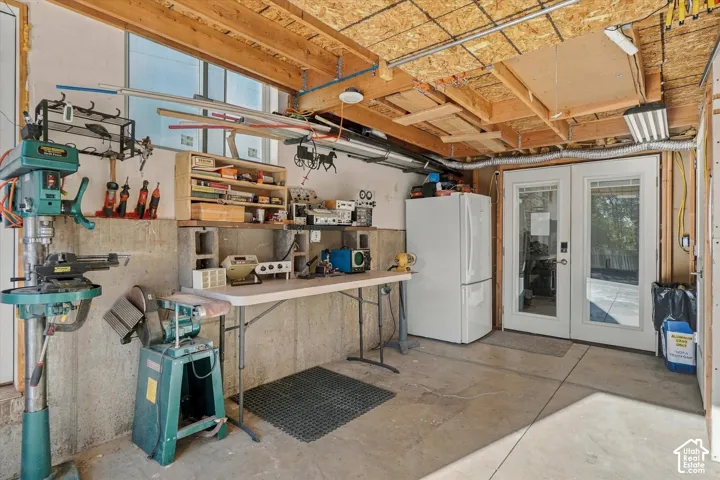 Concrete flooring, exposed wood beam ceiling, white double French doors, transom windows, and built-in shelving