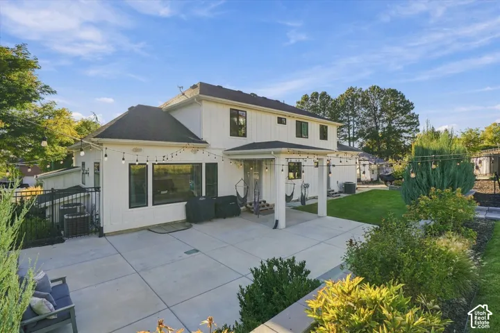 Expansive concrete patio with a covered outdoor area, board and batten siding, and manicured landscaping