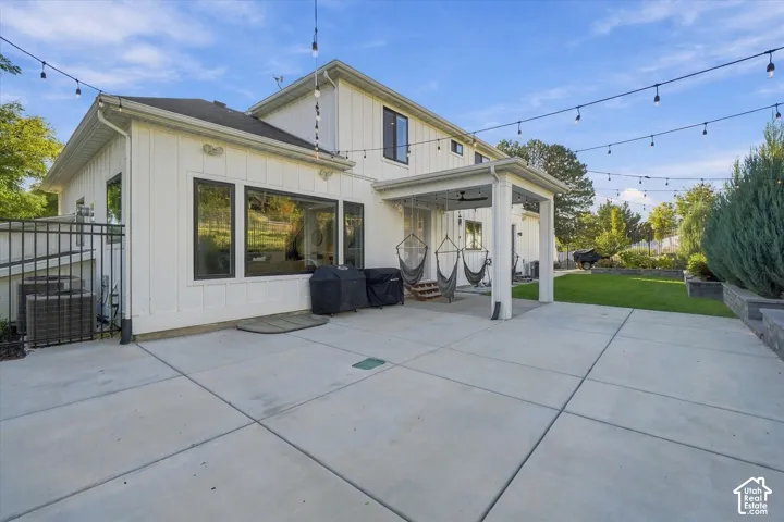 Expansive concrete patio with a covered outdoor area, board and batten siding, and large fixed-pane windows