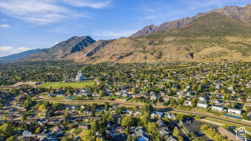 Expansive mountainous backdrop framing a developed residential area with numerous mature trees