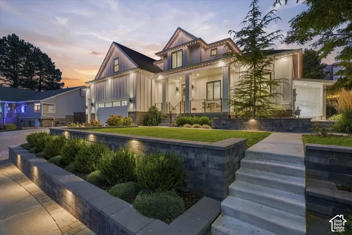 Craftsman-style residence featuring white board and batten siding, stone accents, and a covered front porch with columns