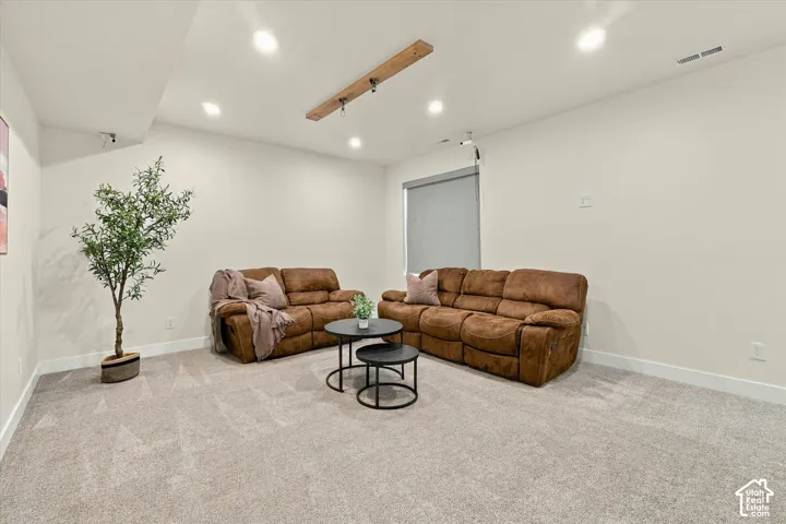 Recessed lighting, wood beam light fixture, light gray carpet, neutral wall paint, and white trim