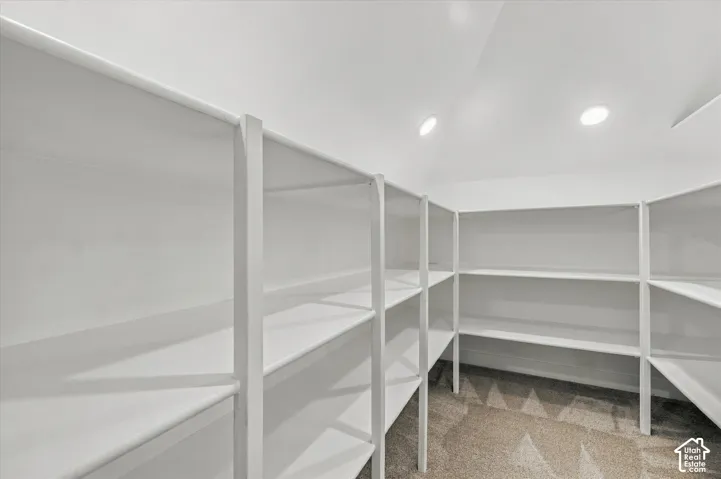 Spacious storage room featuring custom white shelving with multiple tiers and compartments, recessed ceiling lighting, and neutral wall finishes