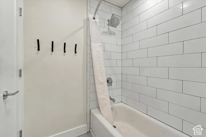 Bathtub with subway tile surround, polished chrome fixtures, and a ceiling-mounted showerhead