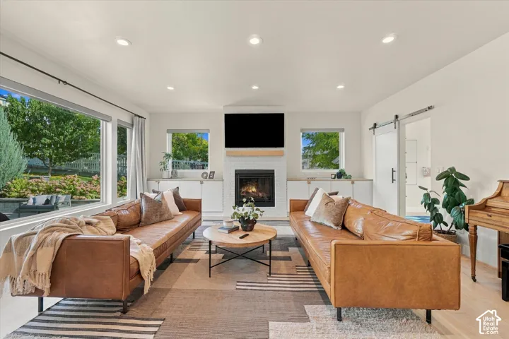 Open-concept living space featuring a fireplace with white subway tile surround, recessed lighting, expansive windows, and a sliding barn door