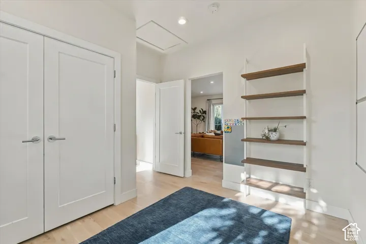 White interior doors, light wood-finish flooring, recessed lighting, and a five-tier shelving unit with wood-finish shelves