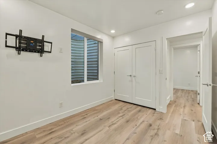 Recessed lighting, wood-finish flooring, white walls, double closet doors, and interior doors with brushed metal hardware