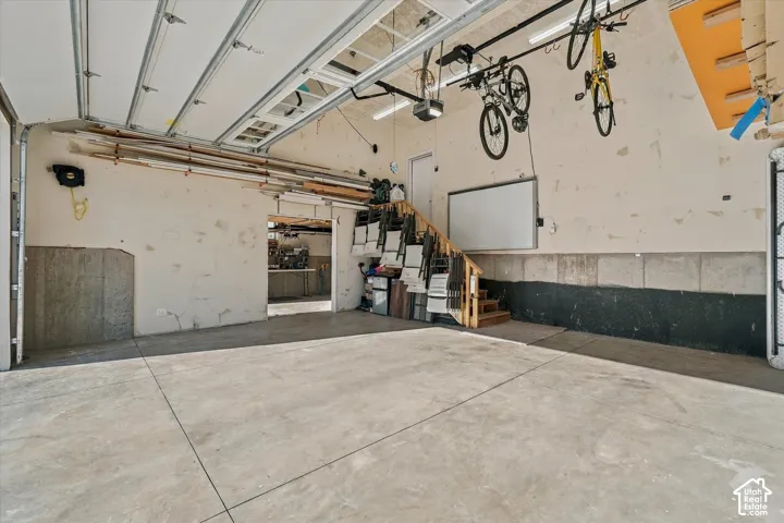 Concrete flooring, open garage door, interior doorway, finished stairs, upper level access