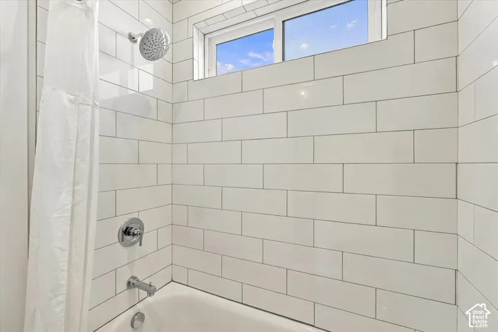 Bathtub with subway tile surround, chrome fixtures, and upper transom window