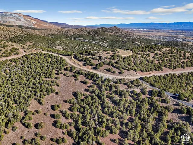 Expansive land parcel with surrounding natural terrain, distant mountain range, and a visible road