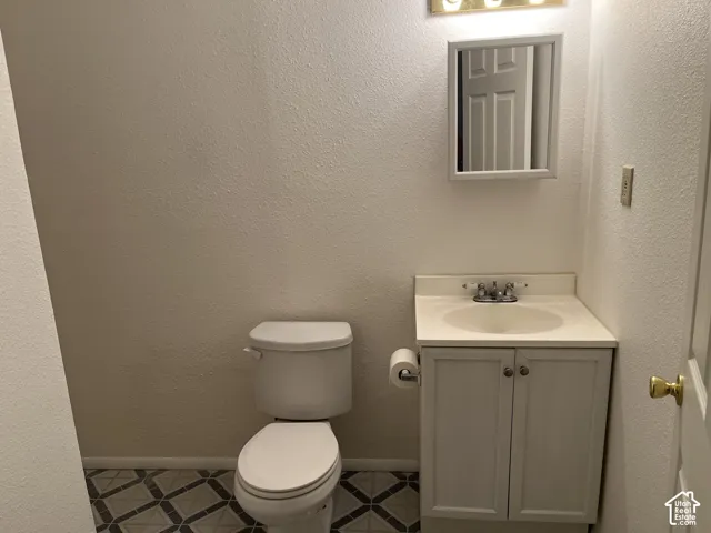 Bathroom featuring a white vanity with integrated sink, a wall-mounted medicine cabinet, and patterned floor tiling