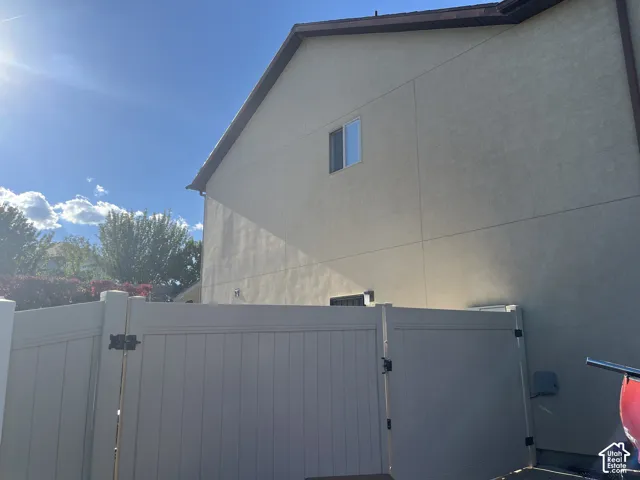Stucco exterior with a single window, brown roofline, and a privacy fence with a gate