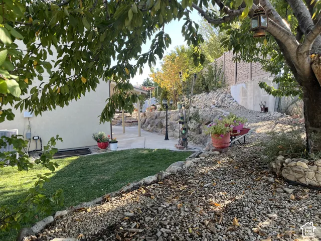 Landscaped backyard featuring a paved patio area, terraced rock garden, and a lawn section