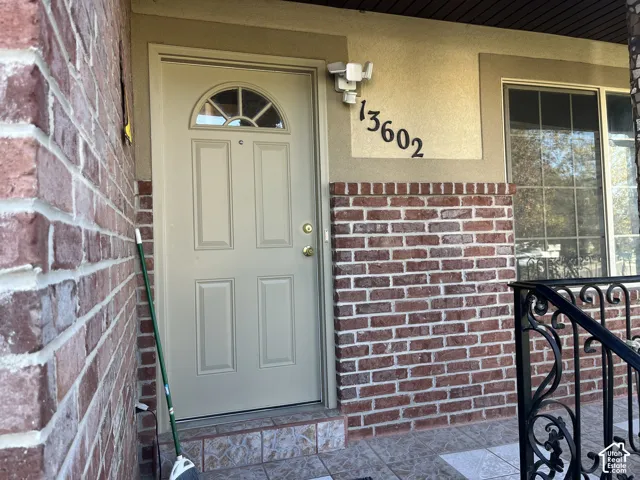 Entry with a paneled door featuring an arched window, brick accents, and a tiled entryway