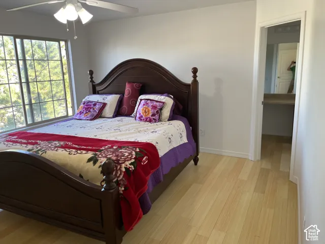 Light wood-finish flooring, white walls, and a ceiling fan with integrated lighting