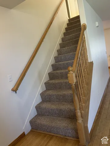 Carpeted staircase with wood handrails and balusters