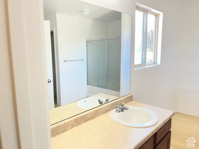 Single vanity with an oval sink, laminate countertop, and wood-finish cabinetry