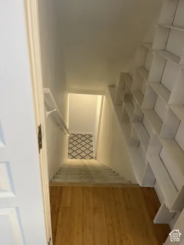 Wood-finish flooring, staircase with patterned risers, and built-in shelving