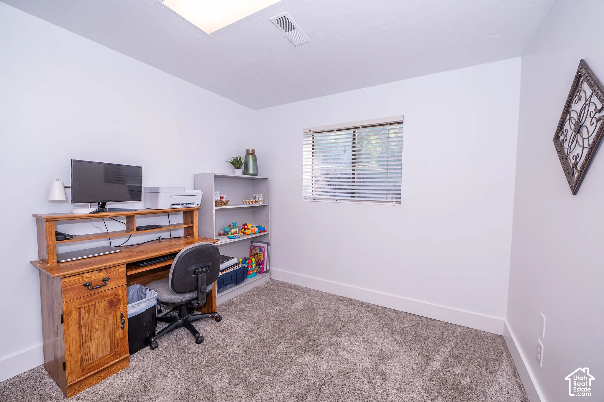 Carpeted room with a single window featuring blinds, a built-in ceiling light, and white walls