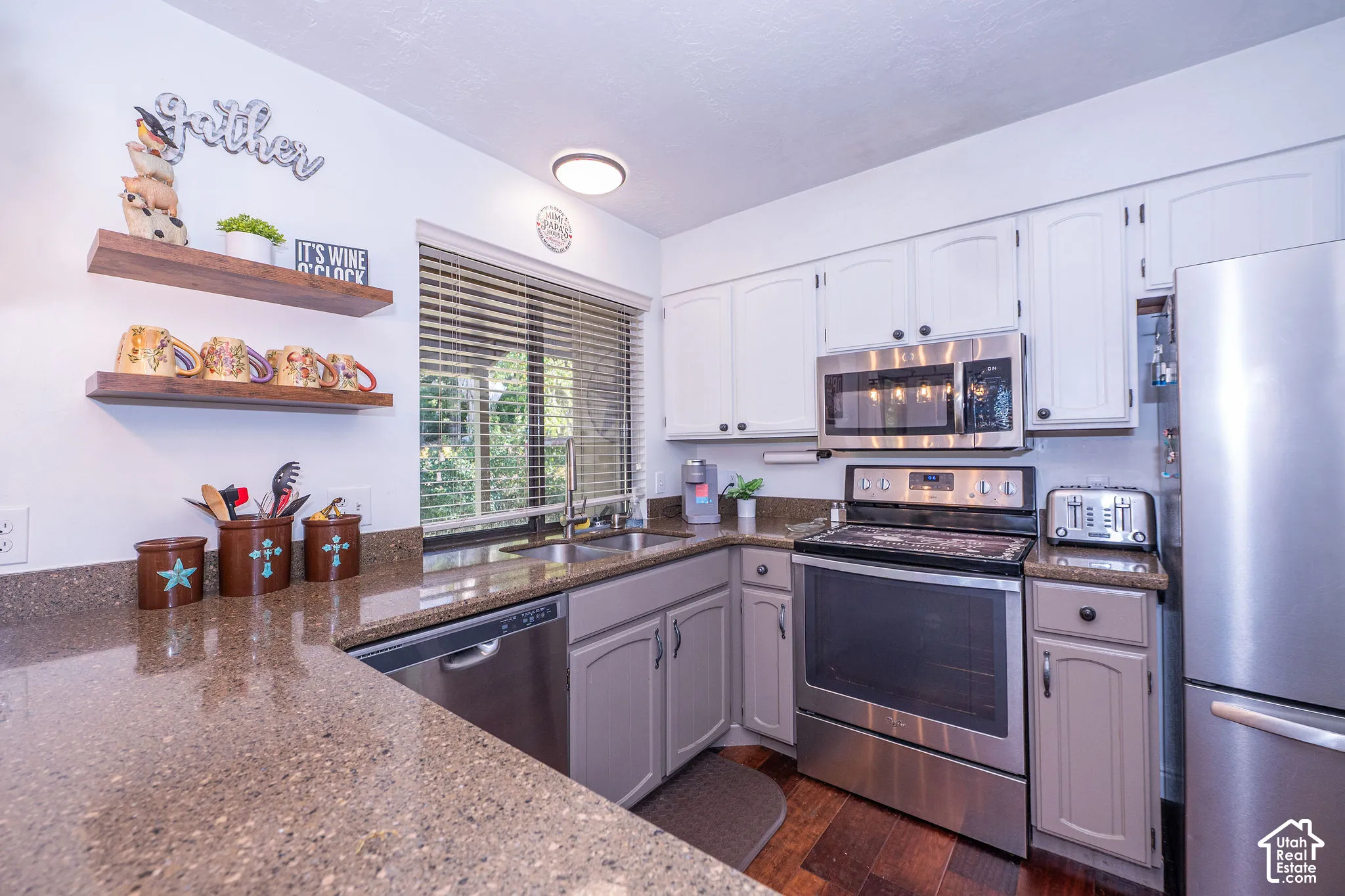 Stainless steel appliances, wood-finish flooring, light-toned cabinetry, and a basin sink