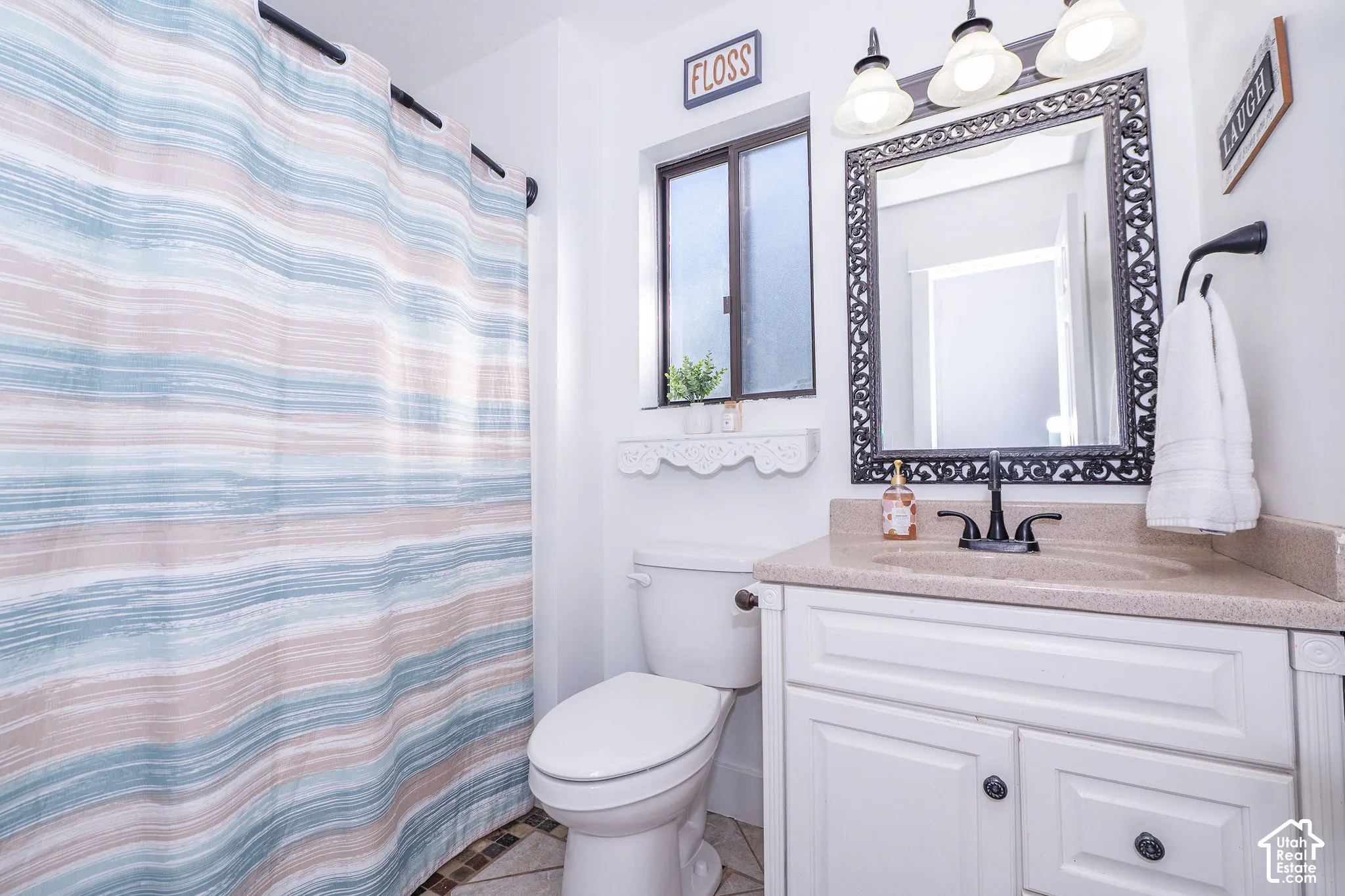 Guest bathroom with a white vanity with a neutral-toned countertop and an ornate framed mirror, complemented by a black wall-mounted faucet