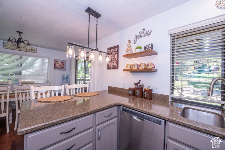 kitchen granite counter with a stainless-steel sink, coordinating dishwasher, and light cabinetry