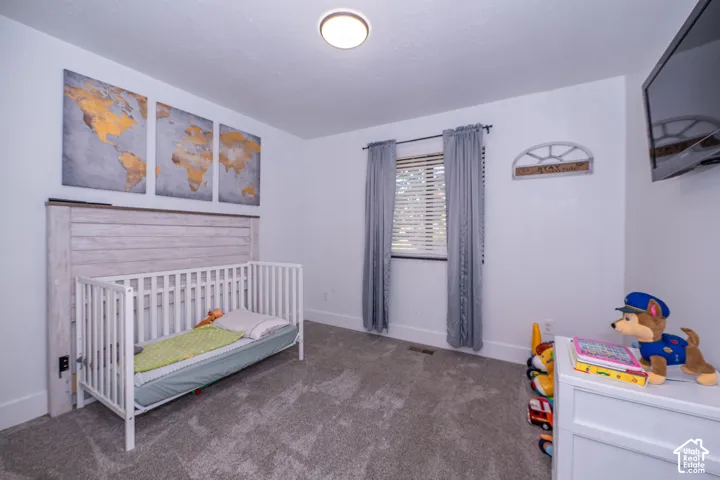 Bedroom 2. White walls, gray carpet, and a window with blinds and curtains