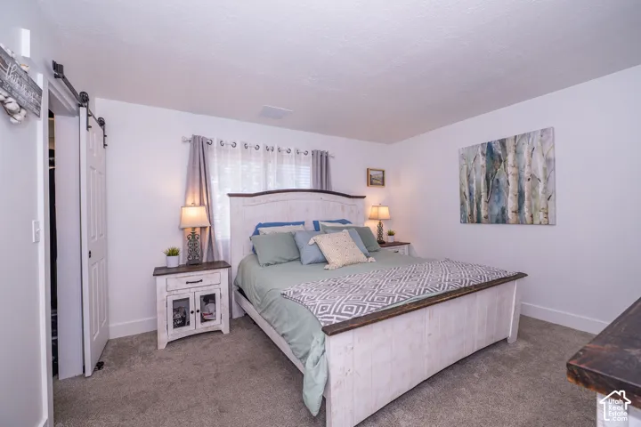 Primary bedroom with white walls, gray carpet, and a white barn door