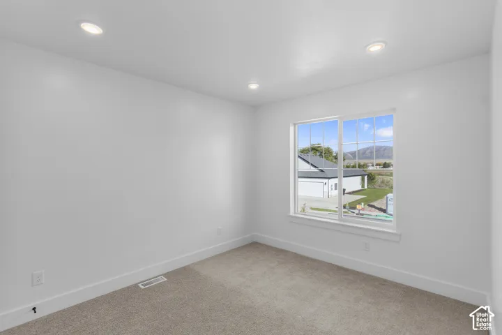 Recessed ceiling lighting, white walls, carpet flooring, large window, mountain backdrop