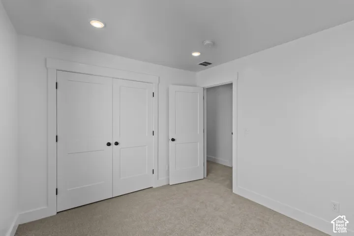 Recessed ceiling lighting, white painted trim, white interior doors with black hardware, and neutral-toned carpeting