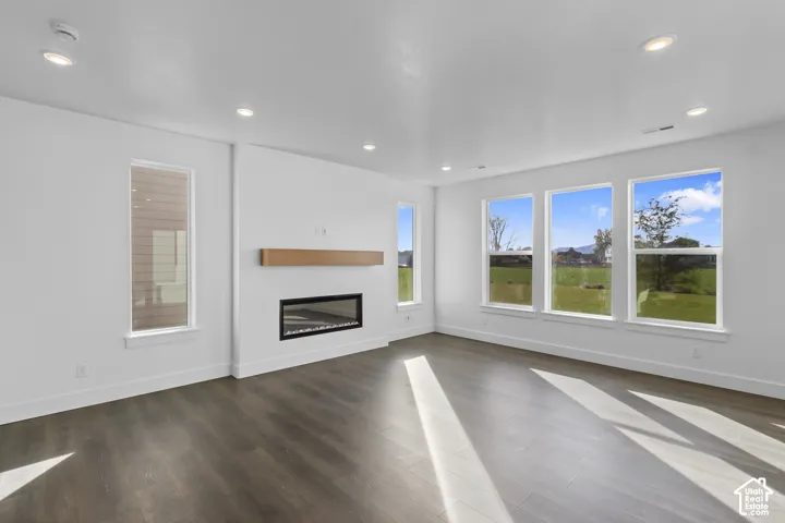 Recessed lighting, wood-finish flooring, a linear fireplace with a wood mantle, and multiple vertical windows
