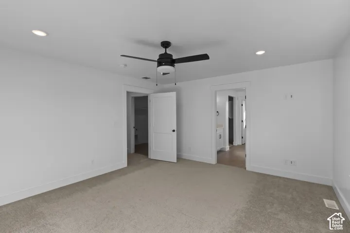 Recessed lighting, ceiling fan with light fixture, white interior doors, and neutral carpeting