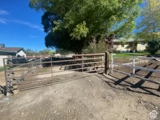 Gated property access with a metal bar gate and white wooden fencing