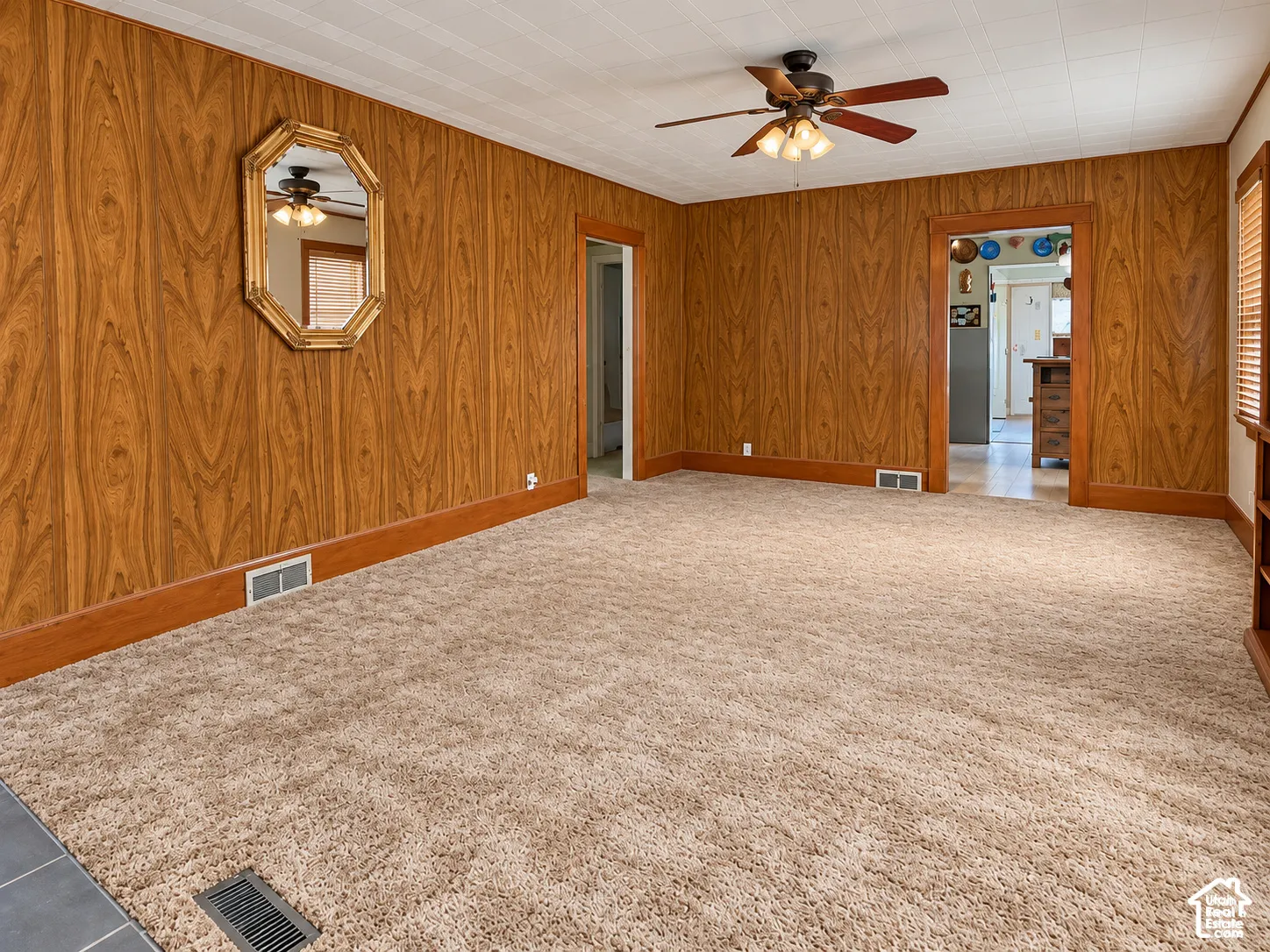 Wall paneling with wood-tone trim, textured ceiling, and a ceiling fan with integrated lighting