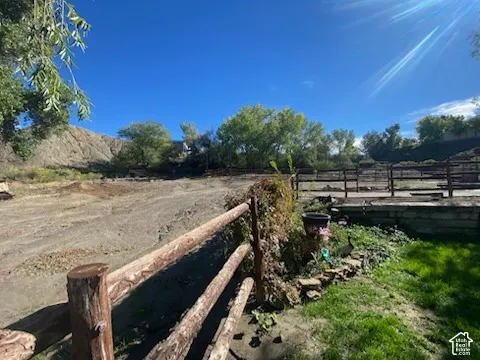Expansive outdoor area featuring natural wood fencing, a grass lawn, and mature trees