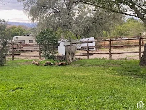 Expansive outdoor area featuring a split-rail fence, mature trees, and a distant mountain backdrop