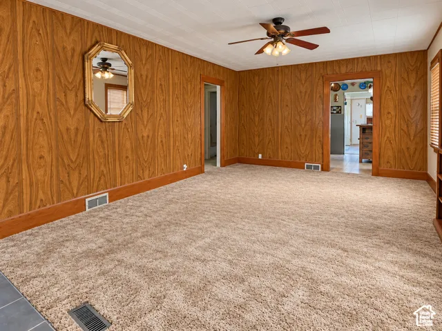 Wall paneling with wood-tone trim, textured ceiling, and a ceiling fan with integrated lighting