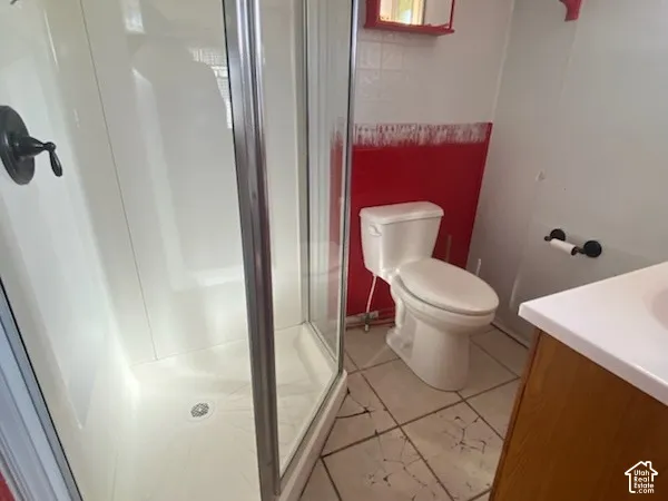 3/4 bath off of the laundry area.  Shower enclosure with a clear glass door, a white toilet, a mirrored medicine cabinet, and a vanity with a white countertop